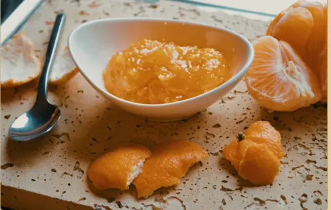 Citrus fruit purée in a bowl beside peeled fruit